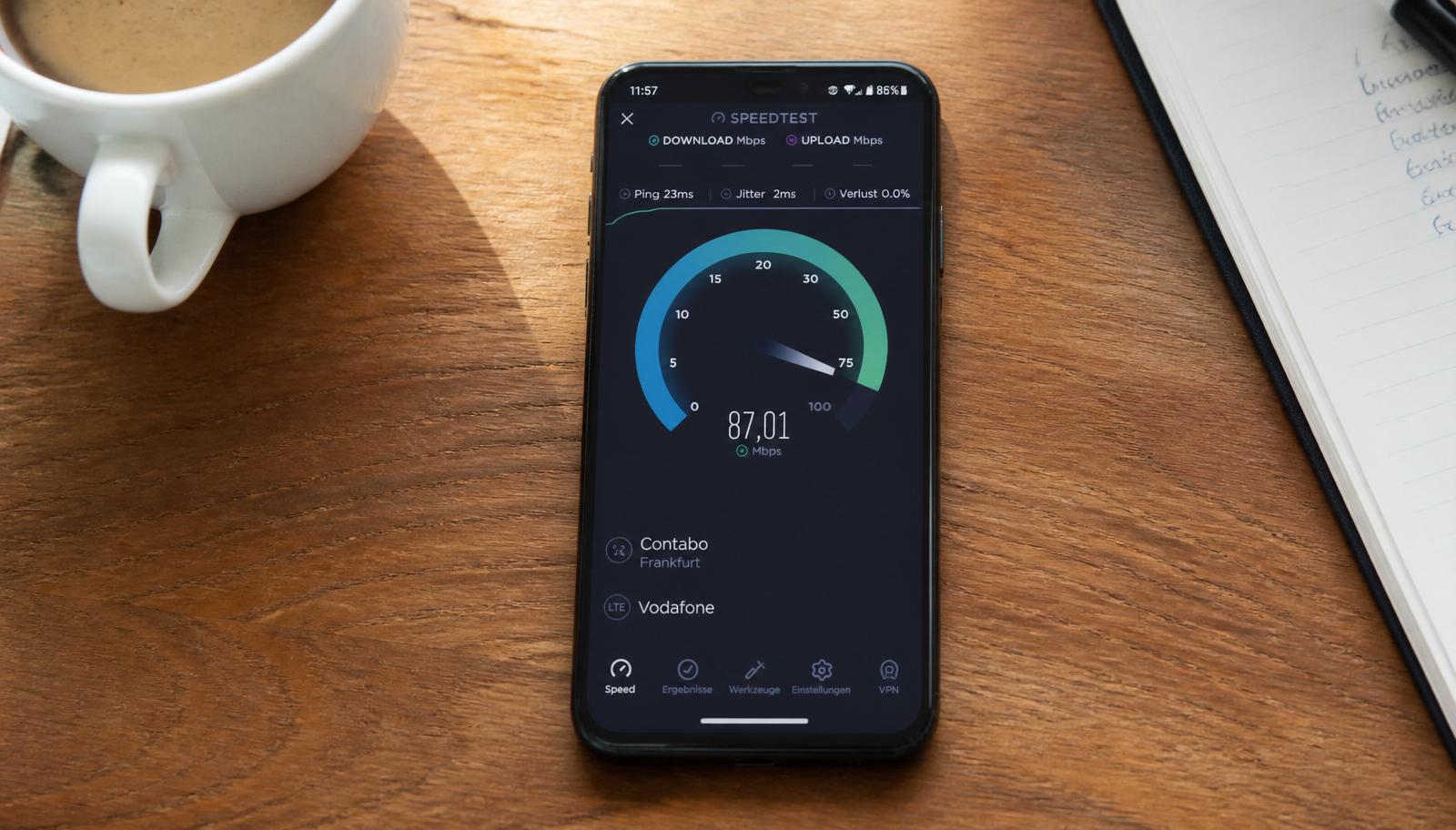 Smartphone-Screen mit Speedtest-Ergebnis von 87 Mbit auf Küchentisch