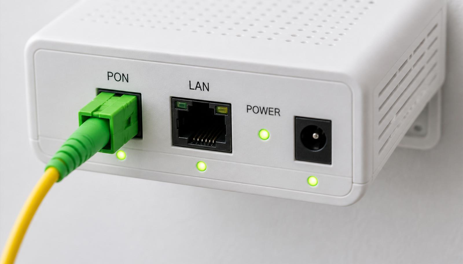 Nahaufnahme eines Optical Network Terminal mit beschrifteten PON- und LAN-Anschlüssen und grünen Status-LEDs