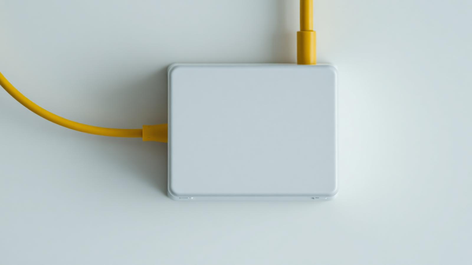 Kleines weißes Glasfasermodem an einer Kellerwand mit Kabelanschlüssen und leuchtenden Status-LEDs.